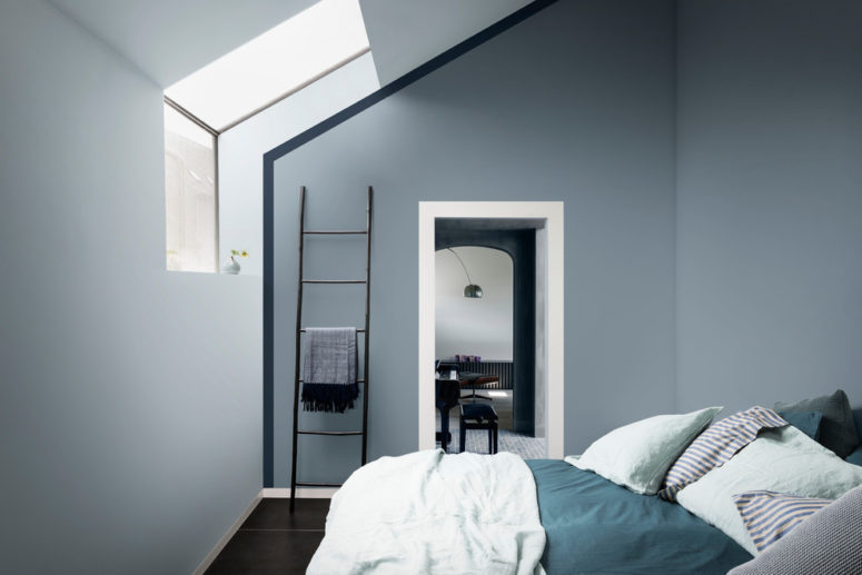 a small and minimalist attic bedroom done in moody blues and with teal and turquoise bedding