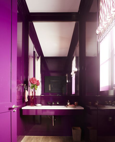 a bright contemporary bathroom done in purple, with an oversized mirror and a floatign sink plus printed shades