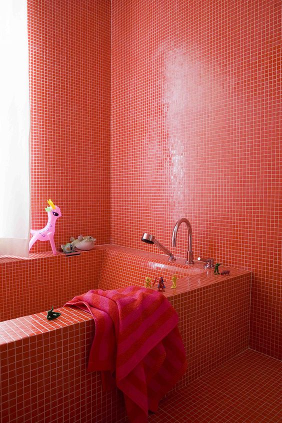 a bright red bathroom fully clad with tiles including the bathtub is a bold idea for a kid