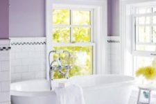 a cozy vintage-inspired bathroom with purple walls and white subway tiles plus a chic clawfoot bathtub