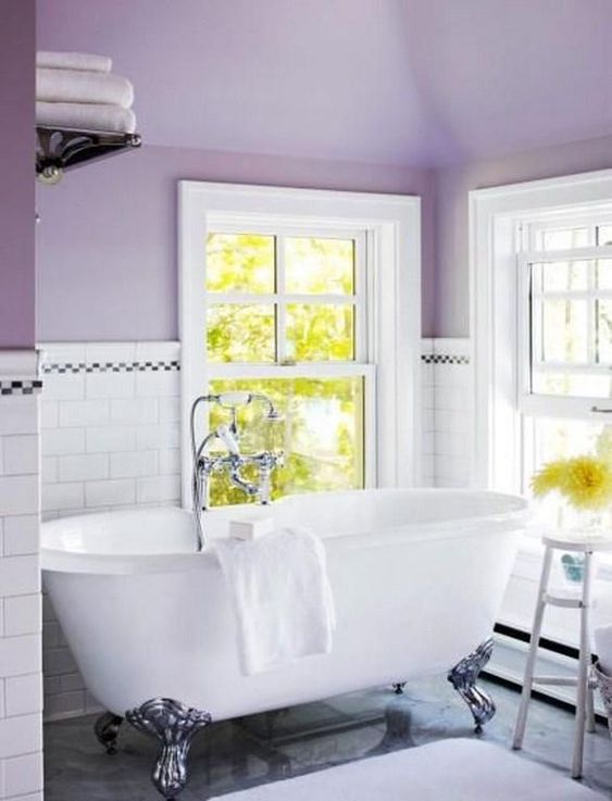 a cozy vintage-inspired bathroom with purple walls and white subway tiles plus a chic clawfoot bathtub
