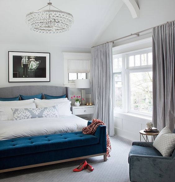 a dove grey and creamy bedroom with a navy bench, pillows and a blue chair