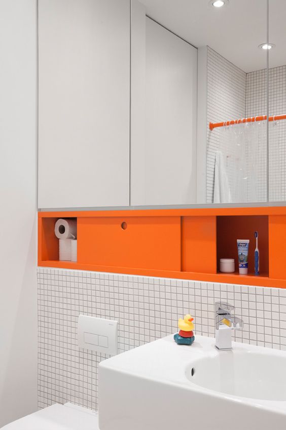 a floating mirror with a storage compartment done in orange is a non-typical way to add color to your space
