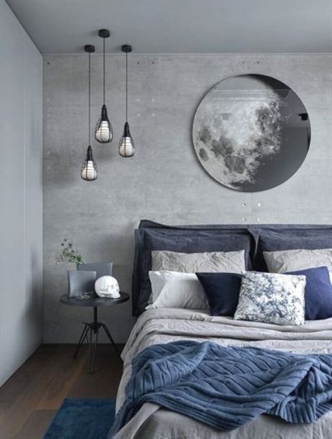a grey bedroom with a concrete statement wall, an upholstered bed and touches of navy blue