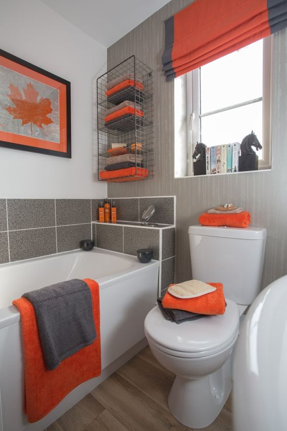 a grey, orange and white bathroom with all the colors mixed up stylishly and some catchy decor elements here and there