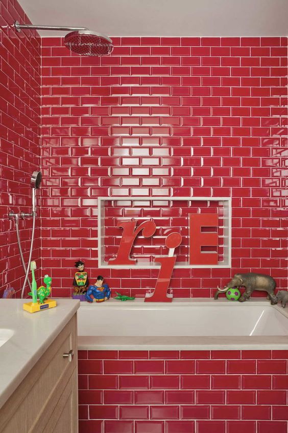 a hot red bathroom clad with tiles and accented with white grout, a neutral vanity and a white sink
