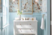 a light blue powder room done with pretty printed wallpaper and a rustic white vanity