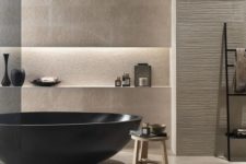 a luxurious beige bathroom with tiles and textural wall panels, a dakr bathtub and lots of bowls and cups