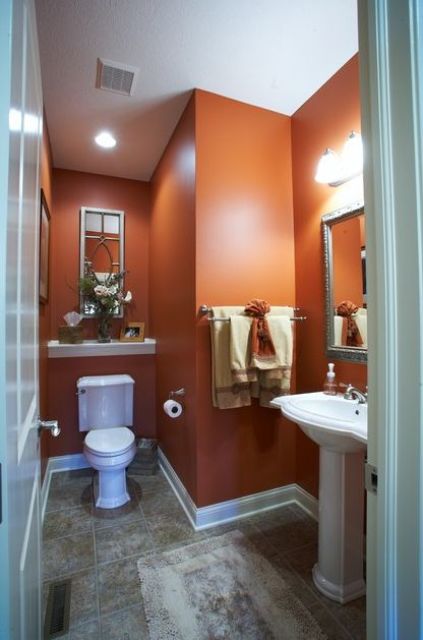 a powder room with rust colored walls, white appliances and a grey floor is a bright and chic idea