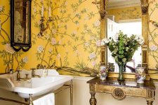 a refined vintage bathroom with beautiful floral wallpaper, a sink on a chic stand, a lovely side table and blooms on it