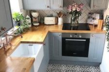 a small farmhouse kitchen done in greys, with a mosaic tile floor, butcherblock countertops and a white tile backsplash done in a chevron pattern