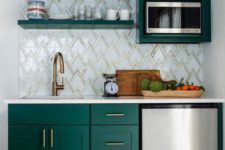 a small kitchen with emerald cabinets, a mosaic tile backsplash, brass hardware, open shelving and metallic appliances