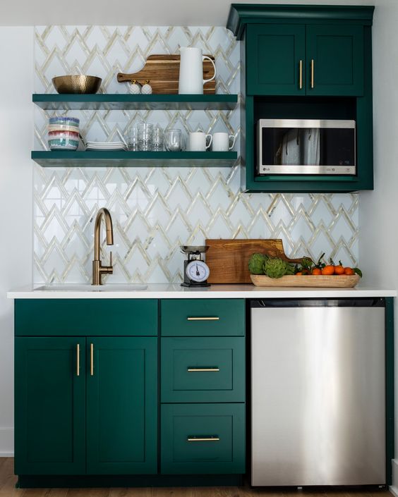 a small kitchen with emerald cabinets, a mosaic tile backsplash, brass hardware, open shelving and metallic appliances