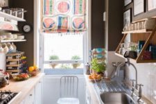 a small monochromatic kitchen with black walls, a white subway tile backsplash, butcherblock countertops and a colorful shade
