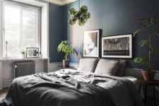 a stylish and relaxing bedroom done in greys and with a navy statement wall, with greenery and green accents