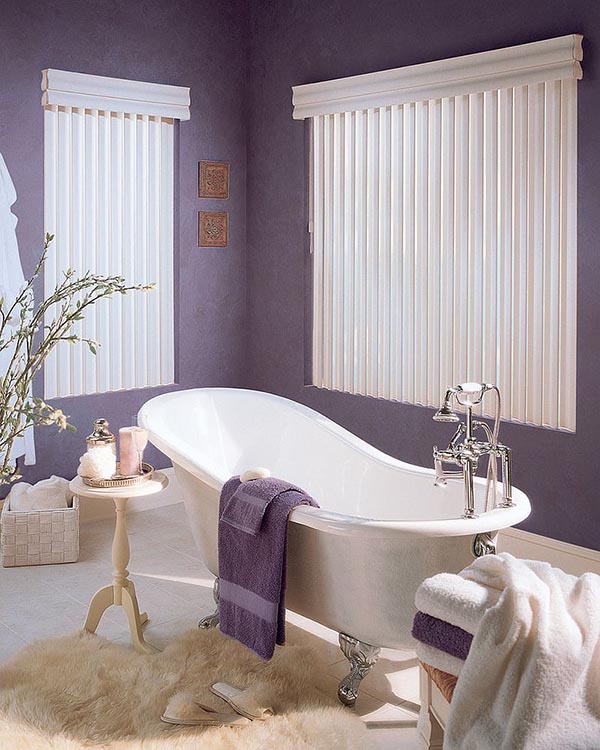a stylish bathroom with purple walls and towels, an elegant vintage bathtub, side tables and a wicker box