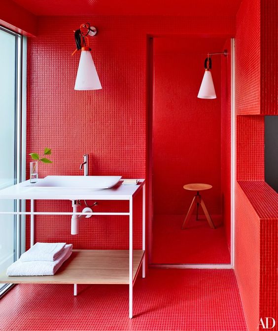 a super bright red bathroom with white appliances and furniture, with white lamps for a bold look