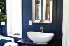 a tiny bathroom done with blue painted wood, wooden beams on the ceiling and a basket for storage