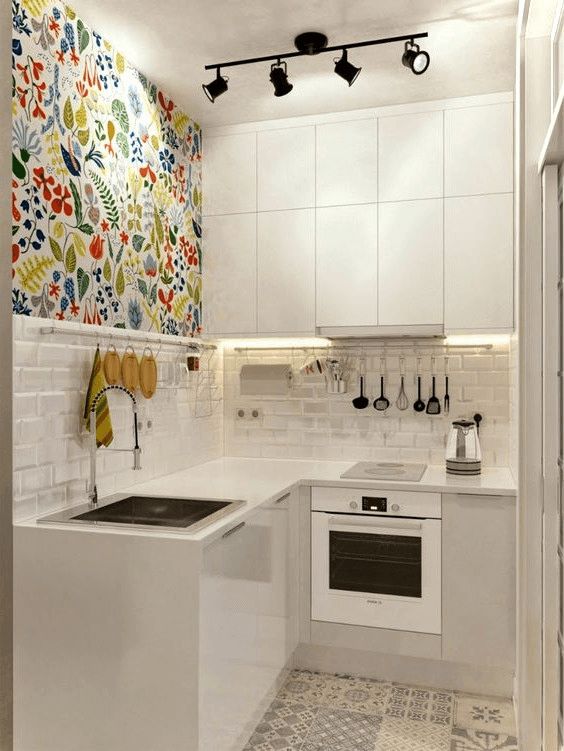 a tiny minimalist kitchen with sleek white cabinets, a colorful wall, a white tile backsplash and a mosaic tile floor