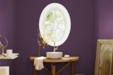 a unique purple bathroom with an oval framed window, a wooden vanity and a vessel sink, an etagere and an artwork