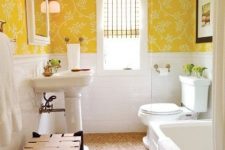 a vintage bathroom with yellow floral wallpaper, white paneling, white appliances, a woven pouf and potted greenery