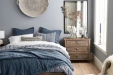 a welcoming light grey bedroom with wooden furniture and blue bedding