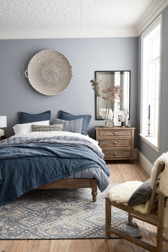 a welcoming light grey bedroom with wooden furniture and blue bedding