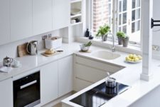 a white minimalist kitchen with sleek cabinets, no handles, a window and simple built-in appliances