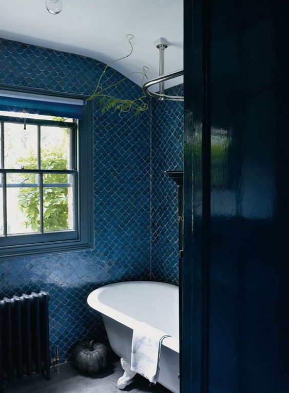 blue fish scale tiles, a navy door, a navy radiator and a blue window frame create a vibrant space