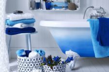 bright blue touches – a rug, towels, fabric baskets and a bright ombre blue clawfoot bathtub for a chic space