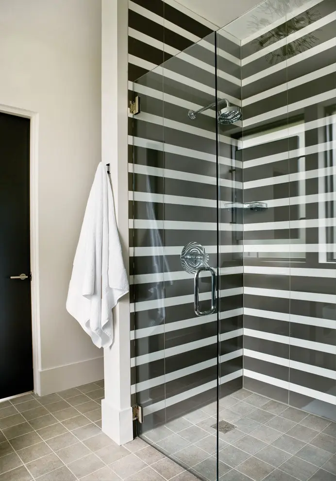 corner shower with horizontal monochrome stripes is difinitely a focal point of this space