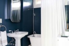 navy painted walls paired with all the rest in creamy shades is a chic idea to create a bold bathing space