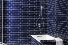 navy subway tiles with white grout and a bathtub clad with the same tiles is a chic and bold contemporary idea