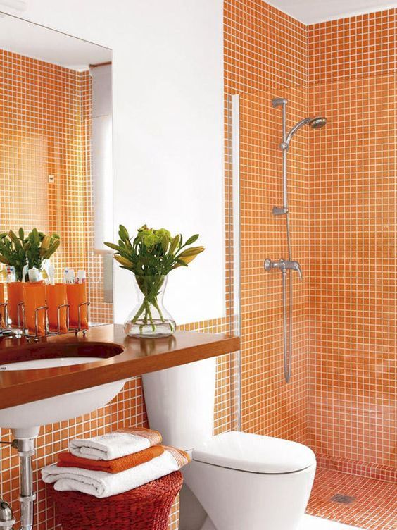 orange tiles on the walls and in the shower can be accented with white grout and orange towels to match