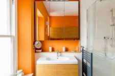 orange walls paired with grey tile floors and all white everything create a fresh and bright summery look in your bathroom