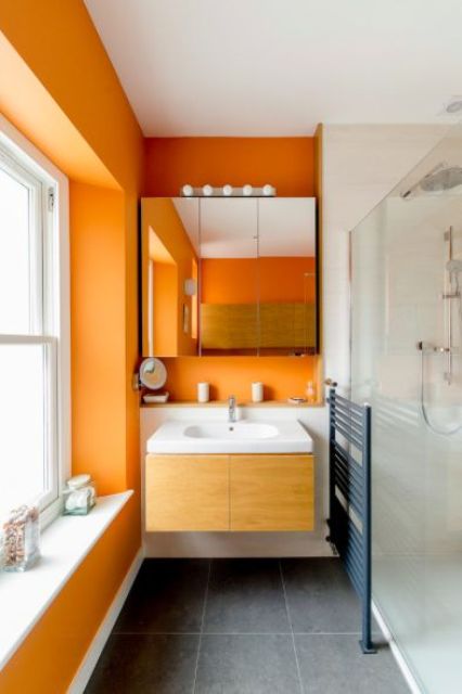 orange walls paired with grey tile floors and all white everything create a fresh and bright summery look in your bathroom