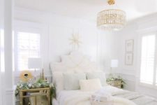 a beautiful glam bedroom in neutrals, with a gold and crystal chandelier, refined furniture, a mirror nightstand and rugs