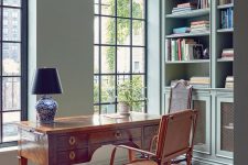 a catchy vintage home office with built-in bookcases, a stained desk and a leather chair, a printed rug and a table lamp