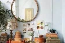 a cute vintage working nook with a vintage desk, chair and a cabinet, a mirror in a vintage gilded frame, greenery and some art