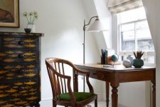 a gorgeous vintage home office nook with a fish print sideboard, a vintage stained desk and a matching stained chair, a floor lamp and a globe