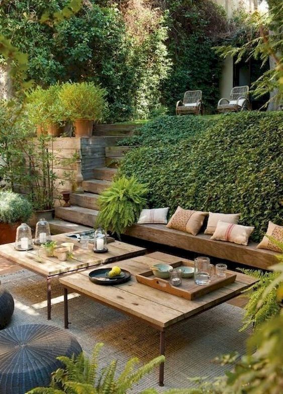 a modern Mediterranean terrace with a built-in bench, modern furniture, wicker ottomans and lots of greenery