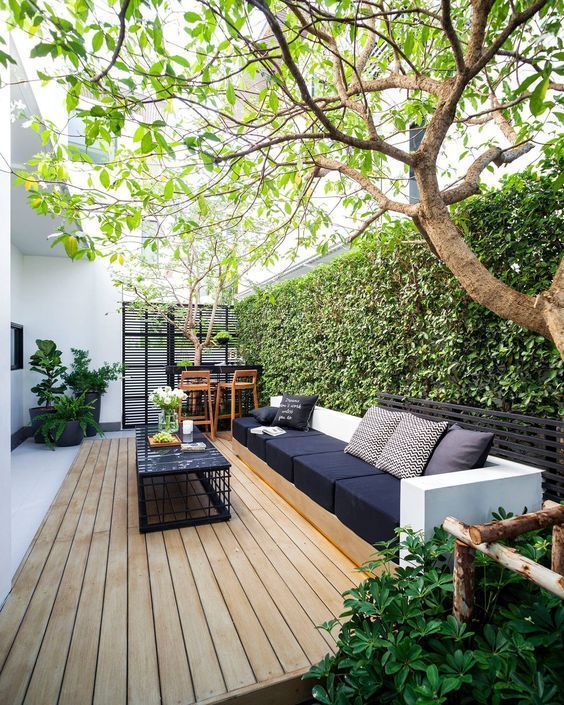 a modern black and white terrace with a living wall, comfy furniture, a black coffee table and a little bar nook