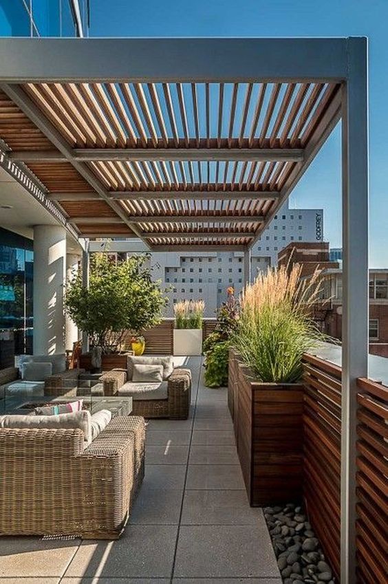 a modern rooftop terrace with wicker furniture, a firepit coffee table and some potted plants here and there
