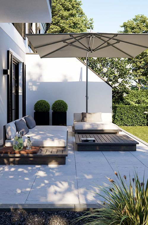a modern terrace with potted greenery, crate furniture and a large umbrella over the space