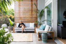 a modern tropical terrace with simple furniture, potted plants, a suspended chair and an animal skin rug