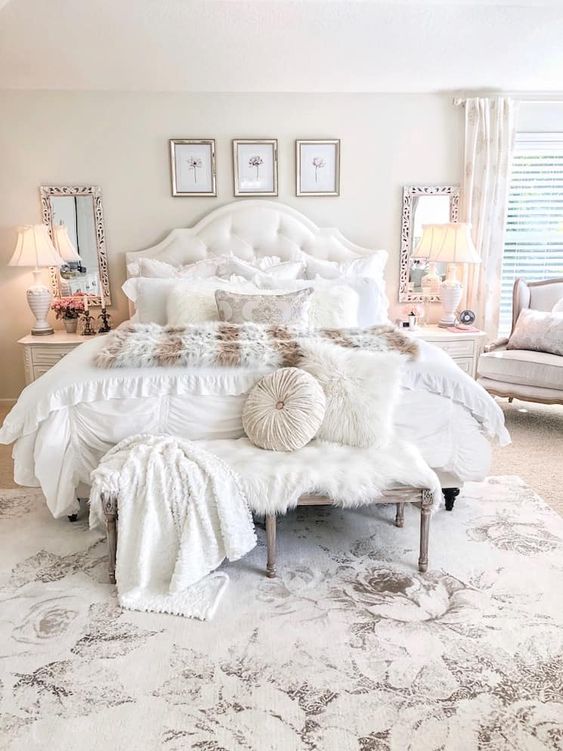 a neutral and pastel glam bedroom with a gallery wall, mirrors, lamps, a shabby chic bench and cool textiles
