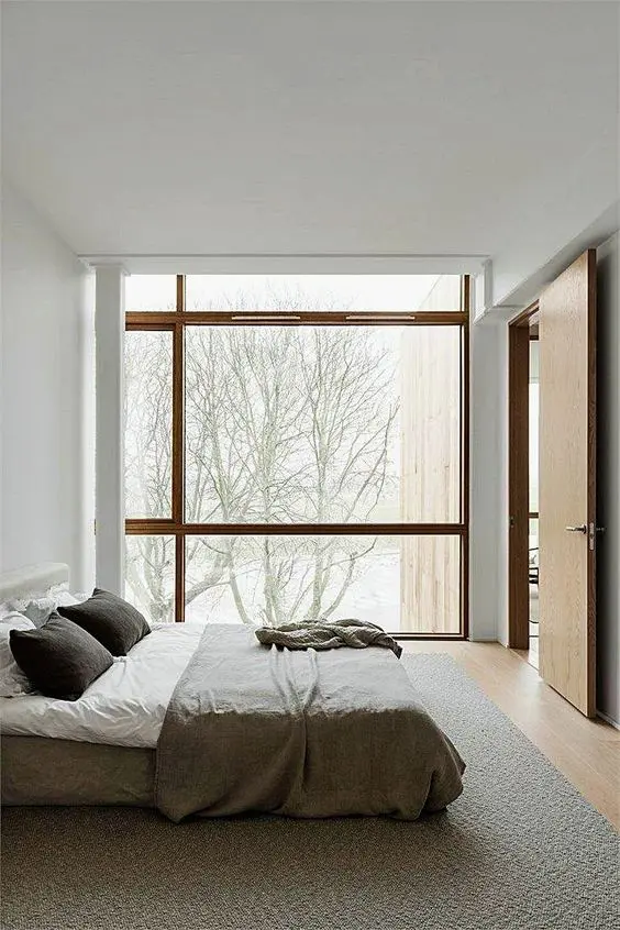 a neutral zen bedroom with a bed right on the floor and a glazed wall to enjoy the views plus neutral linens and bedding
