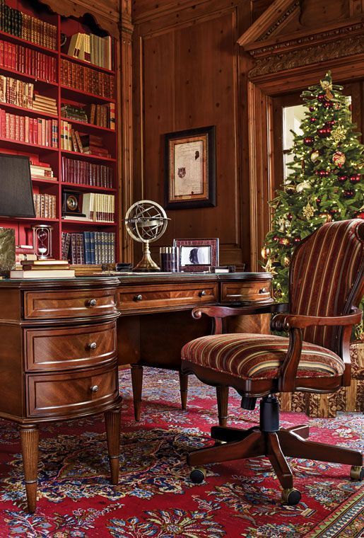 A refined vintage home office fully clad with stained wood, with built in bookcases, a vintage dark stained desk, a matching chair with striped upholstery