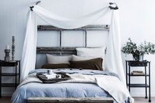 a relaxed zen bedroom with a reclaimed wooden bed, a bench, metal nightstands, blue and grey bedding and a canopy over the bed