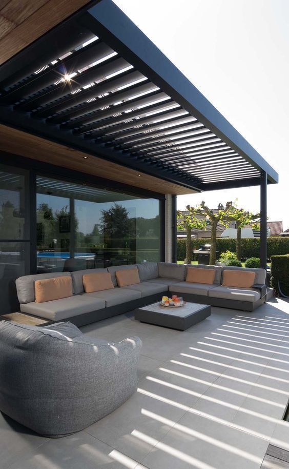 A simple modern terrace under a beamed roof, an L shaped sofa, a beanbag chair and a coffee table